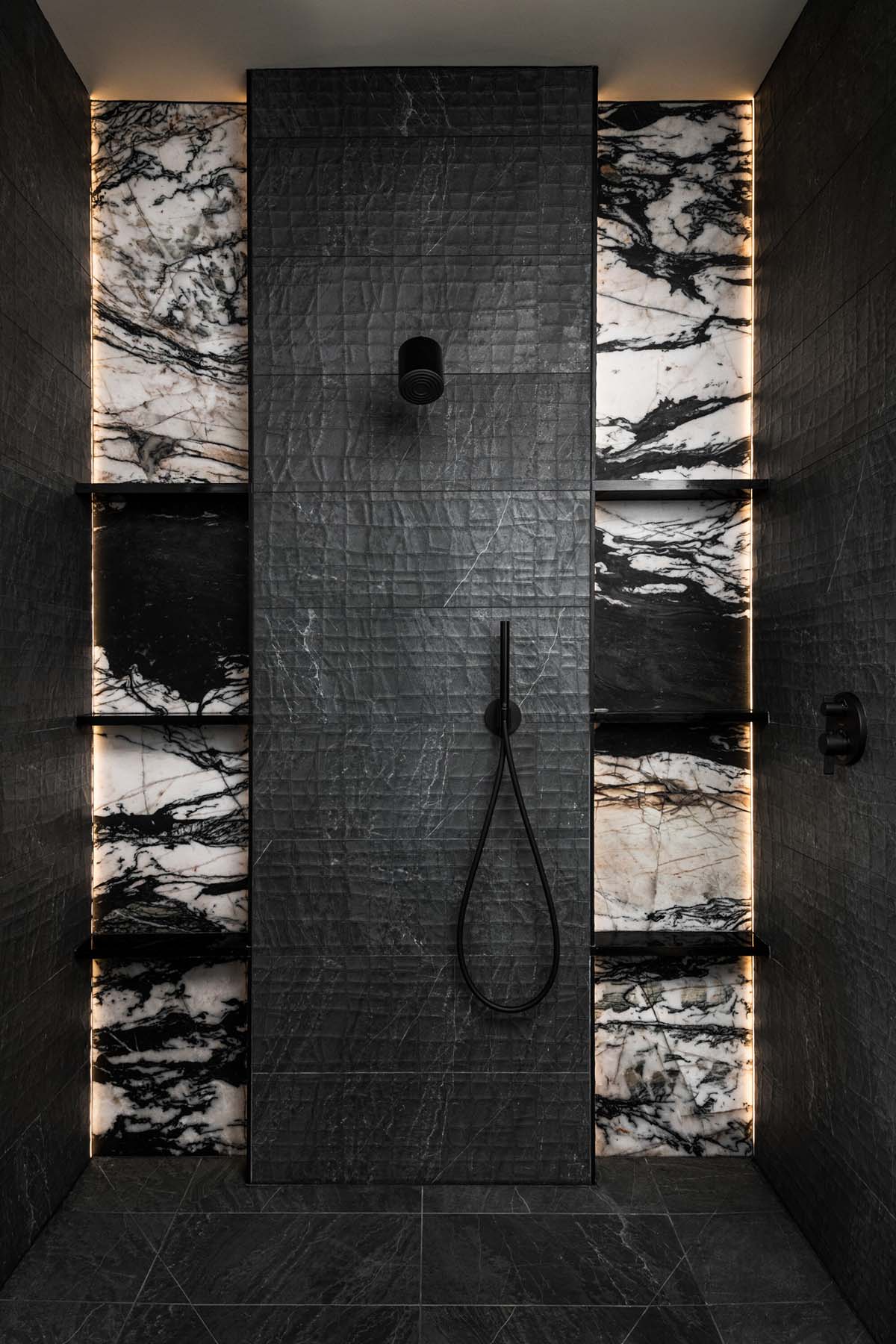 Dark shower with marble niche shelving and matte black fixtures