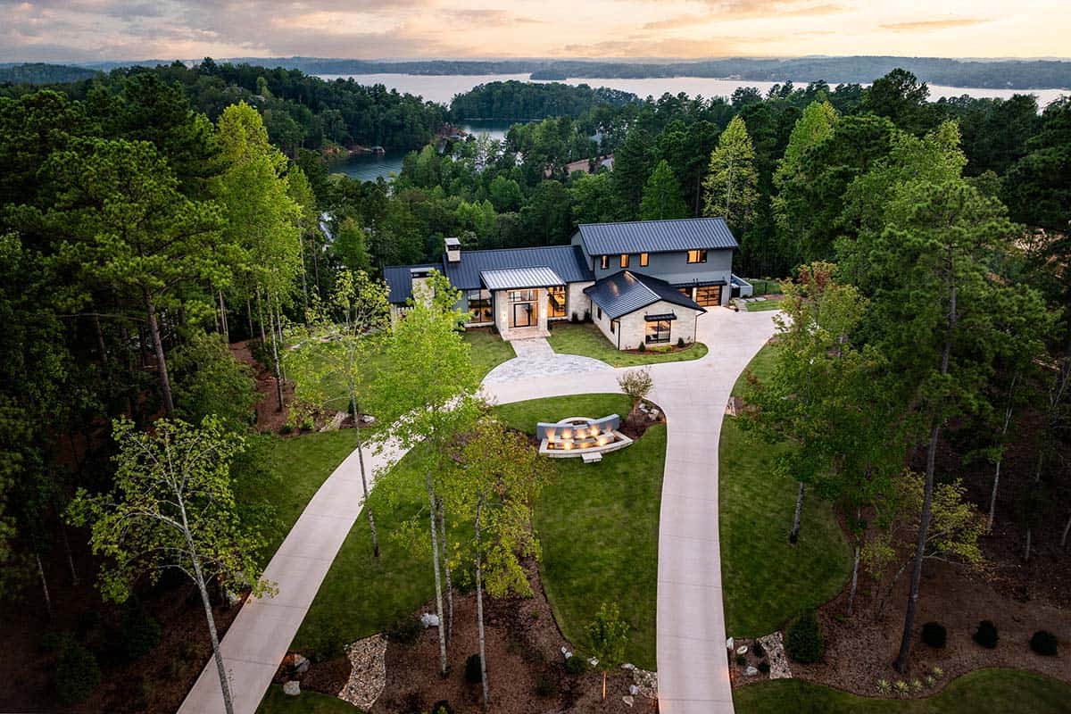 Aerial view of lake house at dusk with circular fire pit driveway