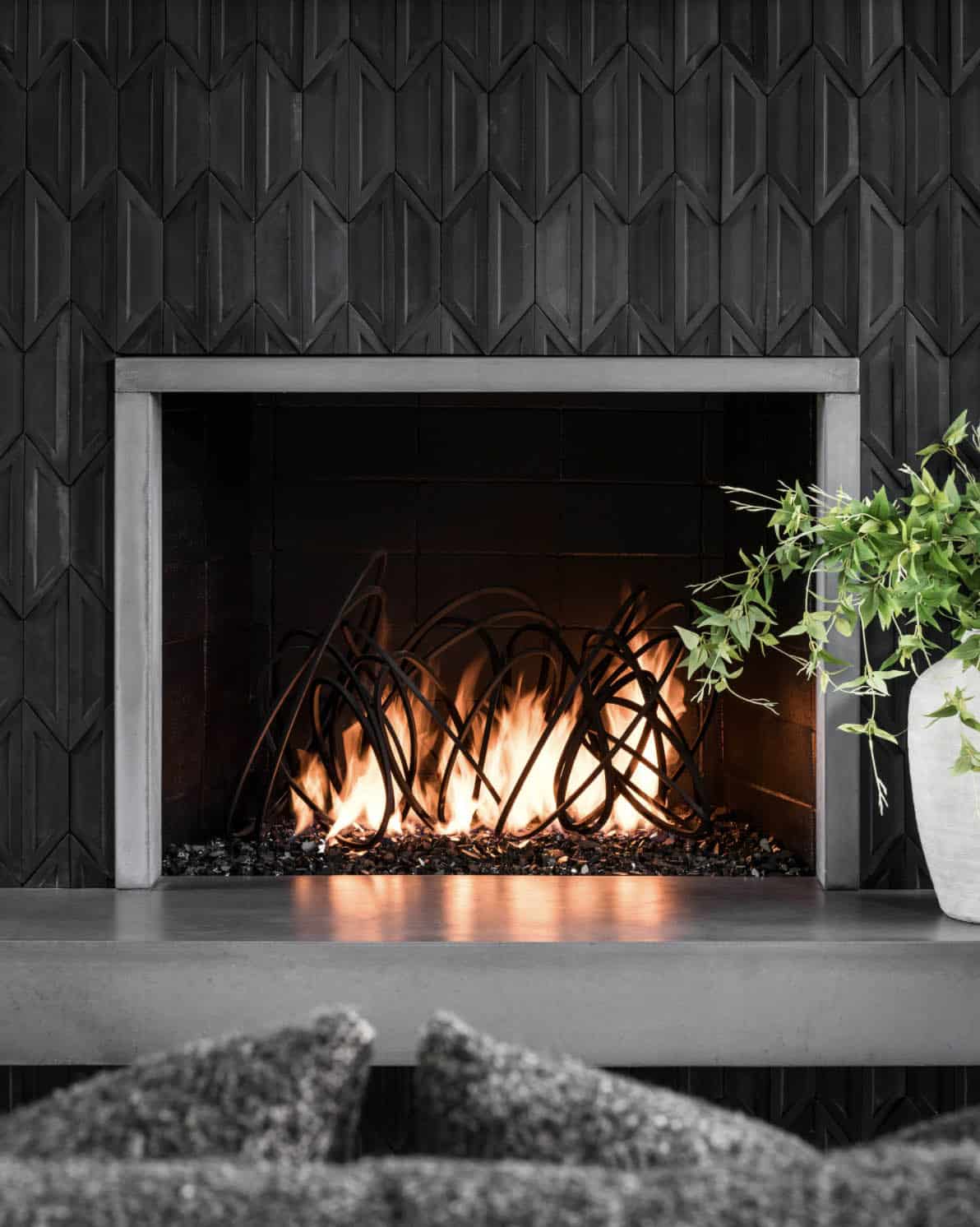 Close-up of gas fireplace with sculptural log art and dark hexagonal tile surround