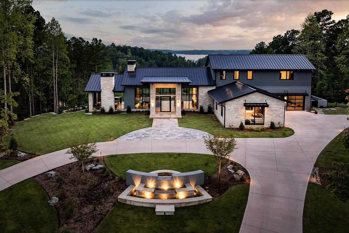 Aerial twilight view of stone-and-metal-roofed home with cascading fire water feature