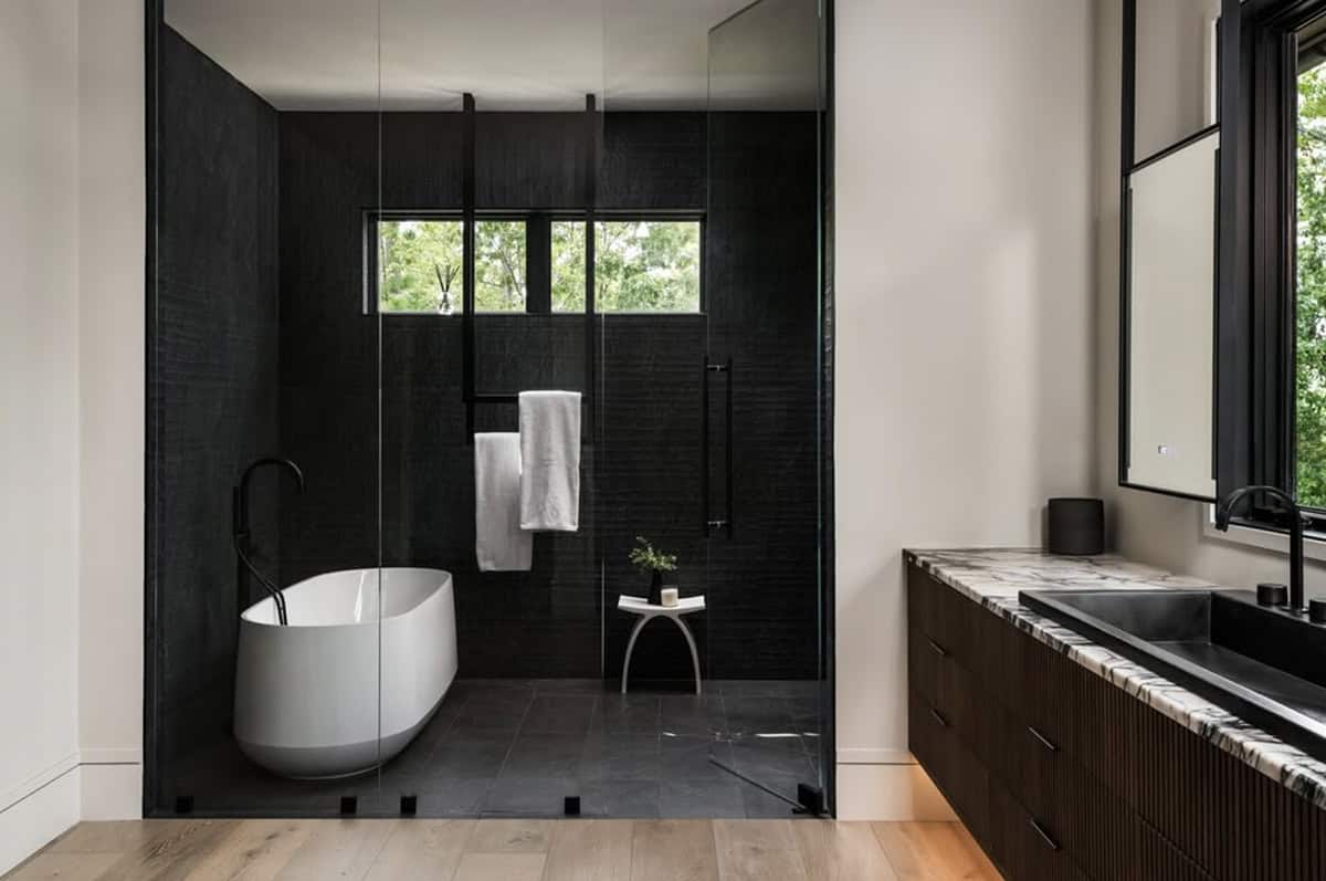 Primary bathroom with black tiled shower, freestanding tub, and marble vanity