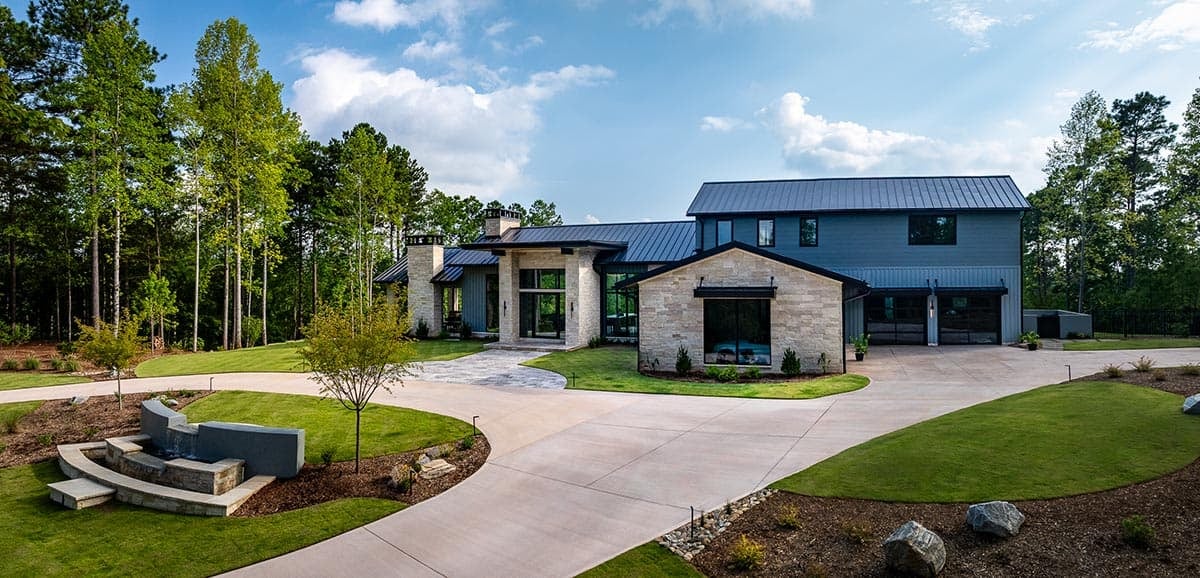 Two-story farmhouse-style exterior with stone accents and water feature