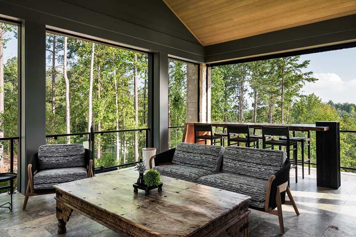 Screened porch with woven lounge furniture, wood coffee table, and forest view