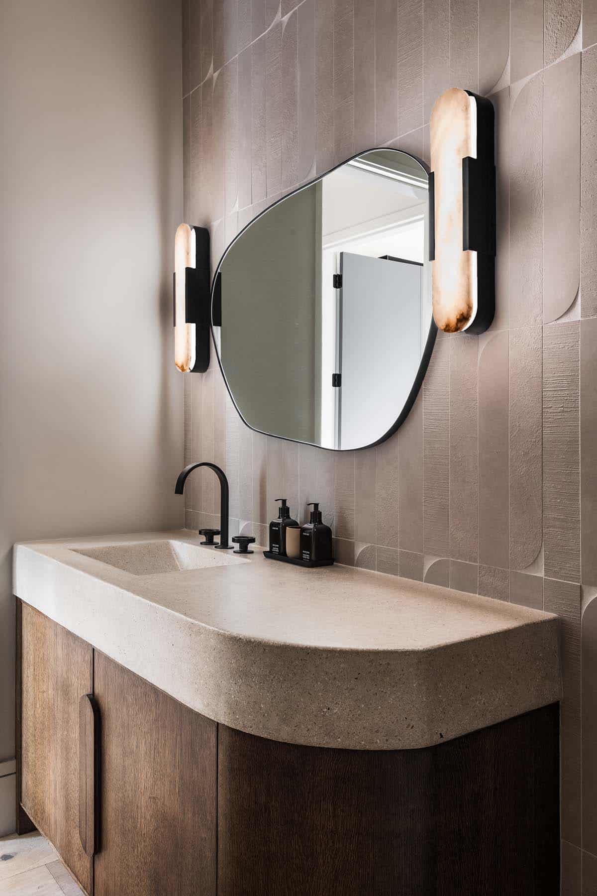Powder room with curved concrete vanity and organic pebble-shaped mirror
