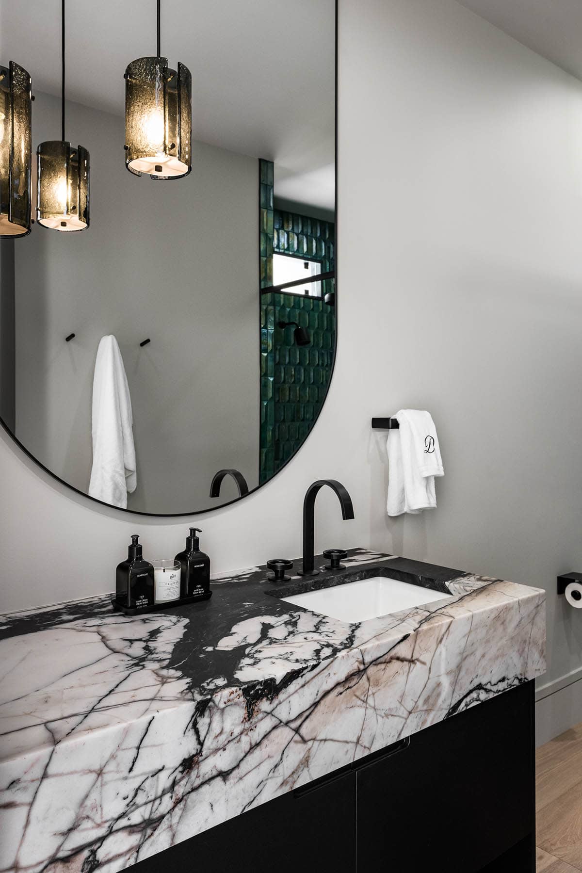 Bathroom vanity with black-and-white marble counter and amber pendant lights