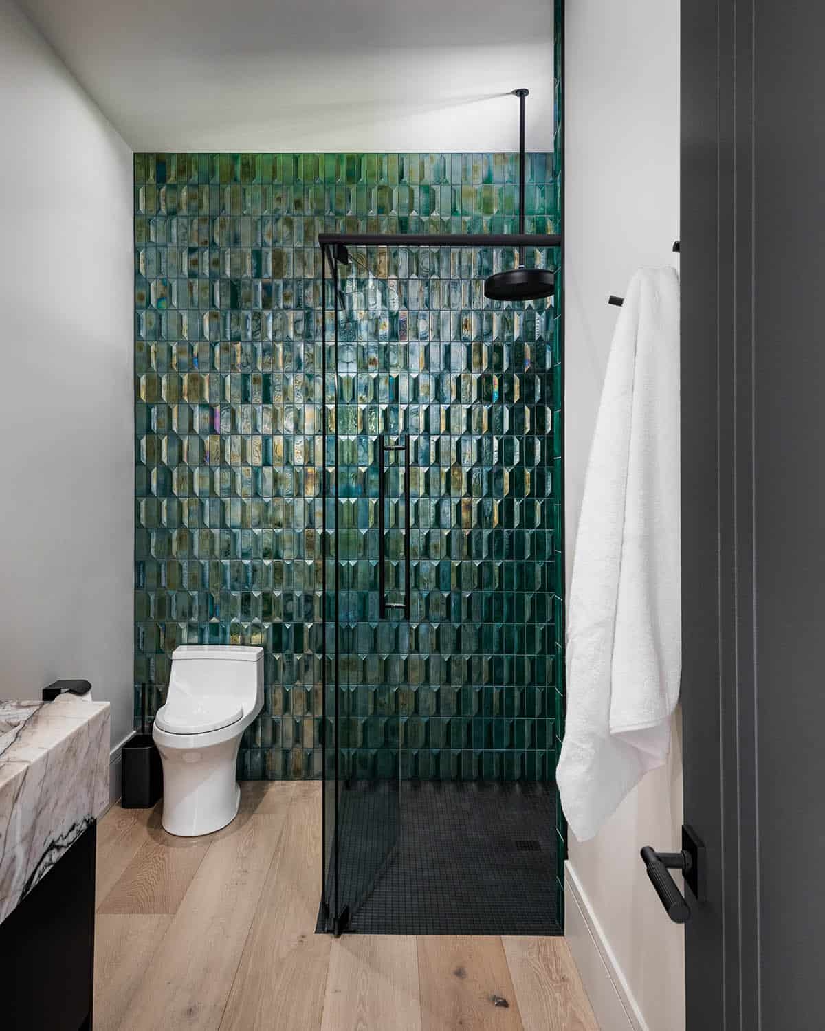 Walk-in shower with iridescent emerald tile and matte black fixtures