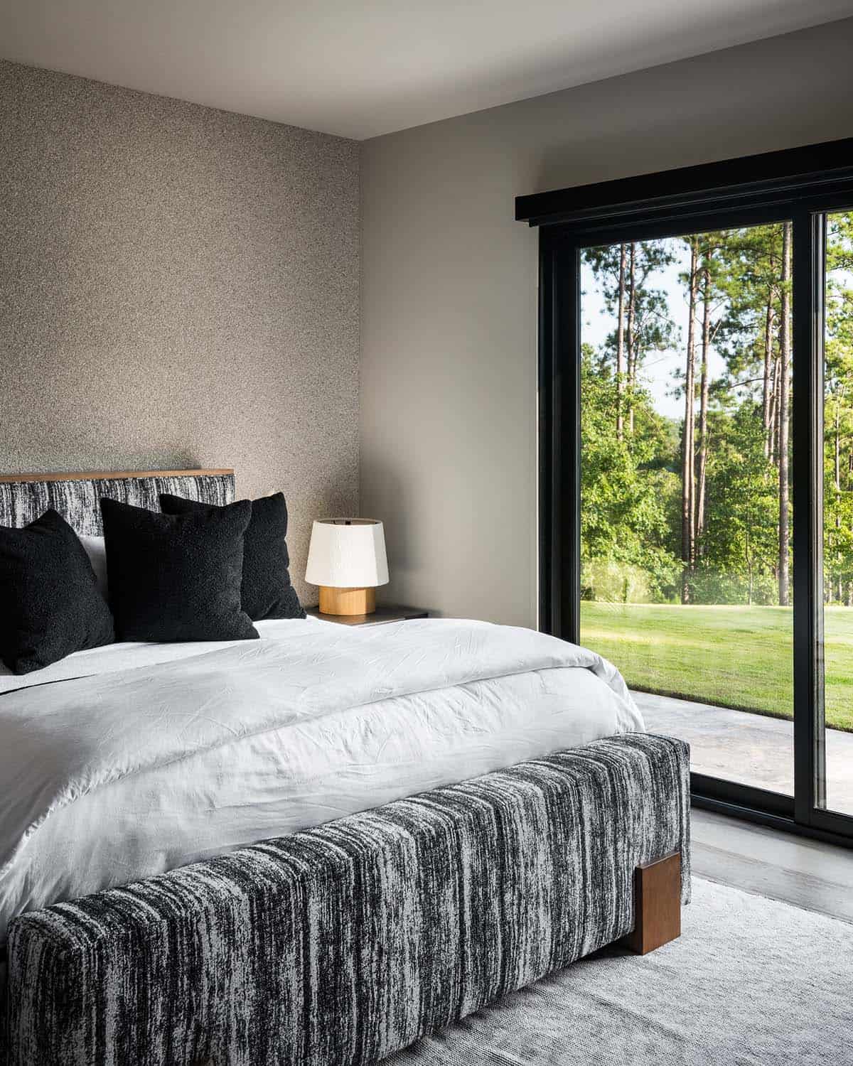 Guest bedroom with textured headboard and sliding glass door to lawn