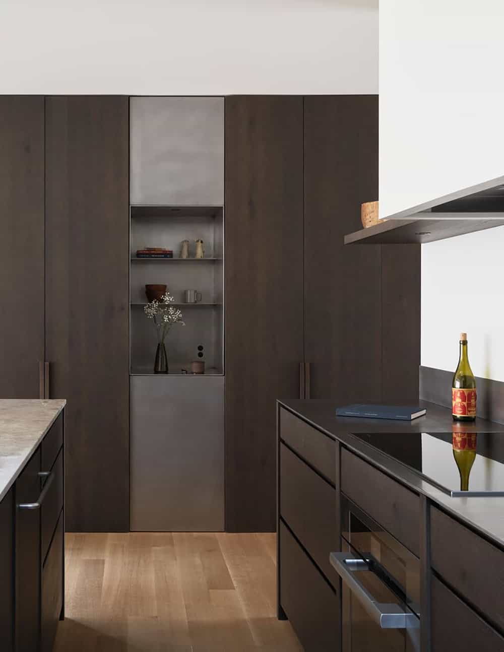 Kitchen with dark stained oak cabinetry, steel-lined open shelving niche, and black stone countertops