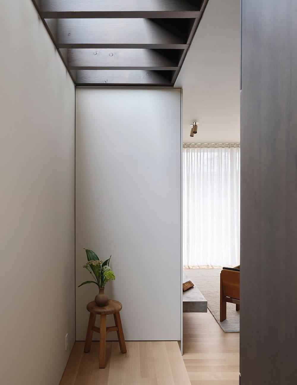 Transition corridor with perimeter skylight, exposed beams, and view into the living room