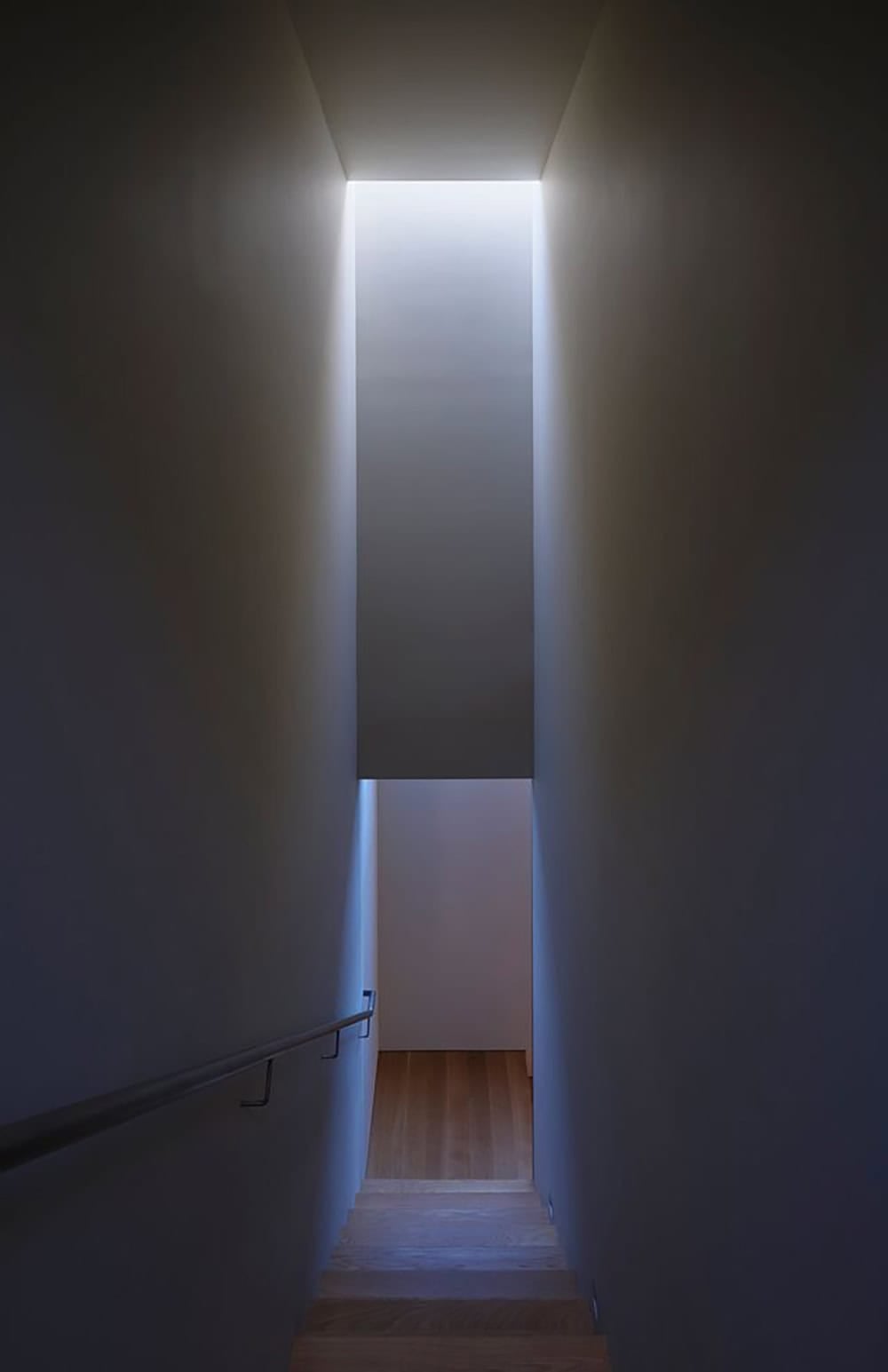 Narrow stairwell with dramatic perimeter skylight casting a column of natural light
