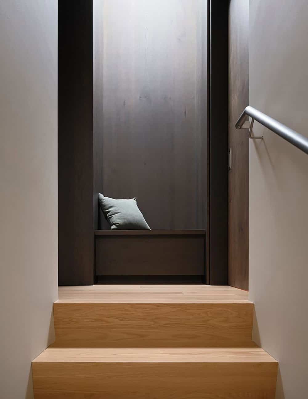 Wood staircase with metal handrail leading to an intimate built-in window seat