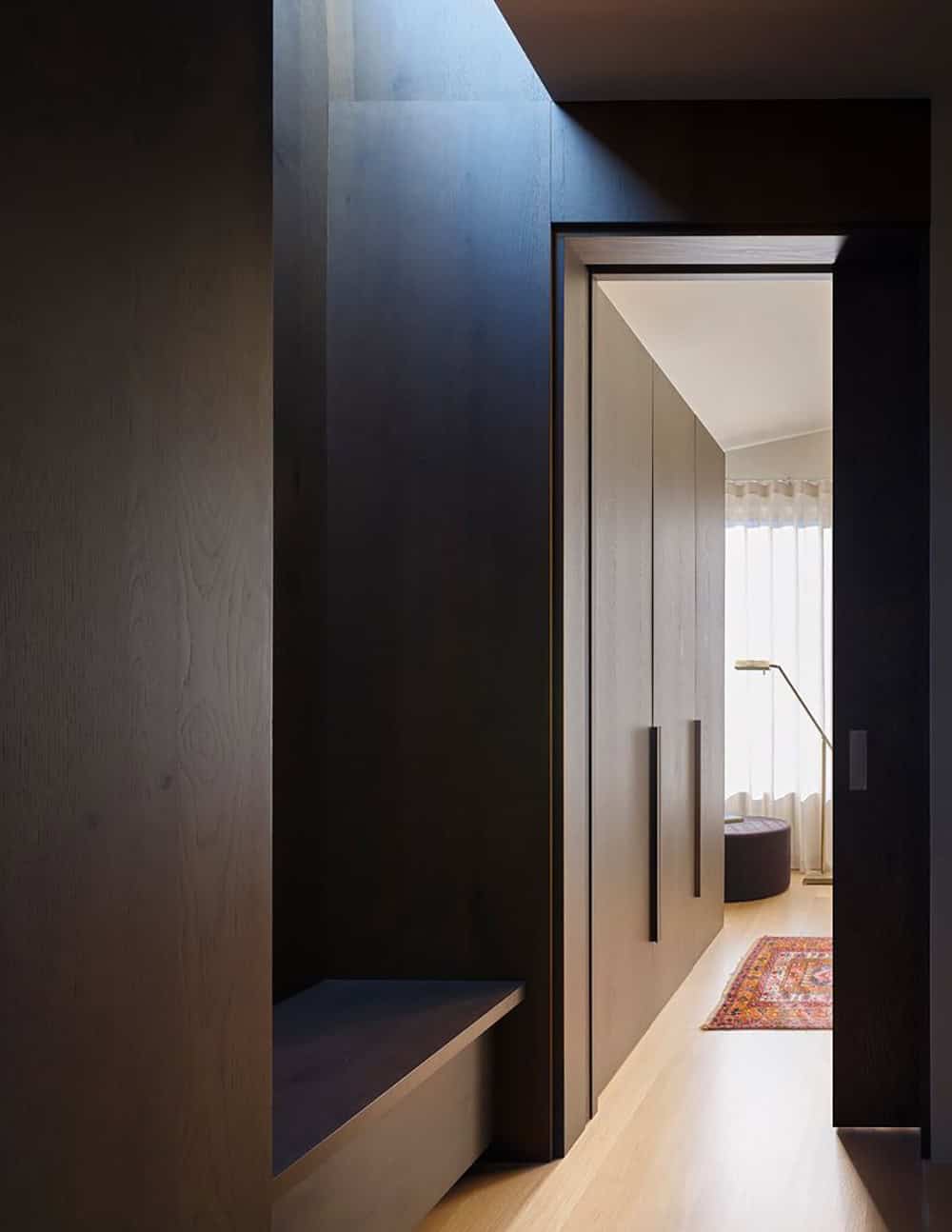 Dark wood upper hallway with built-in bench niche and view into the bedroom