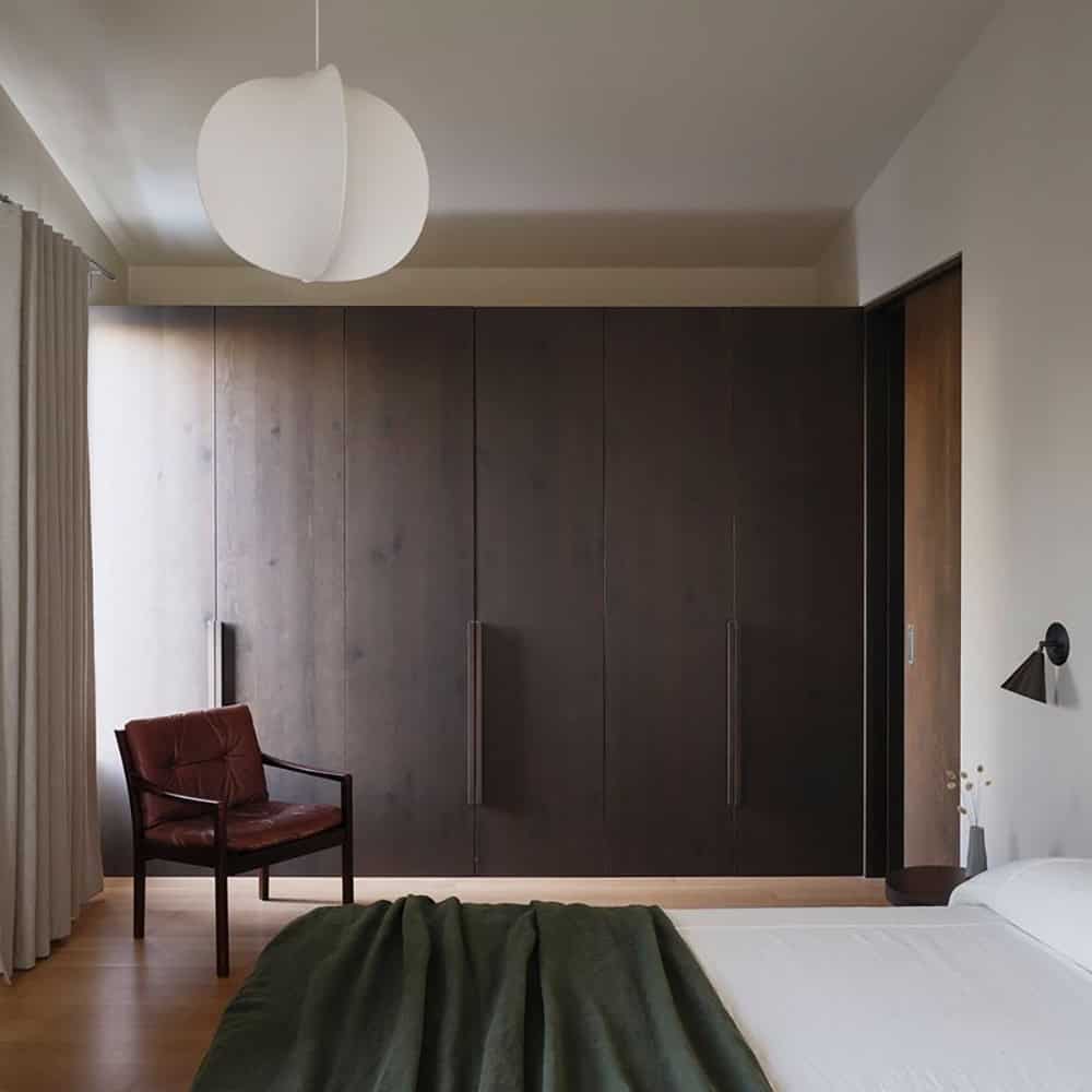 Primary bedroom with floor-to-ceiling dark wood wardrobe and globe pendant light Primary 