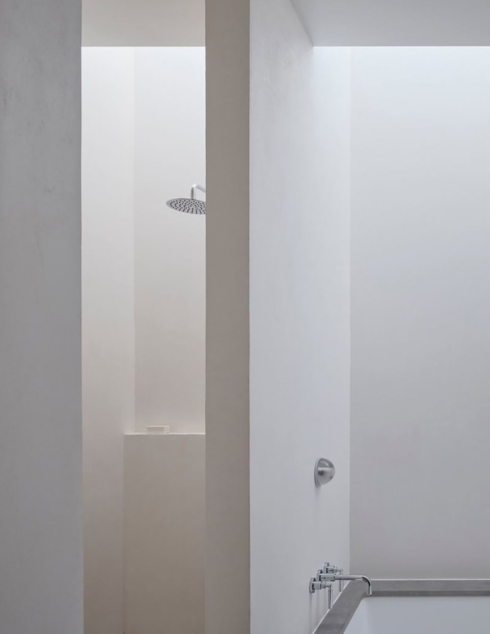 Minimalist shower with perimeter skylight, rain showerhead, and plaster walls