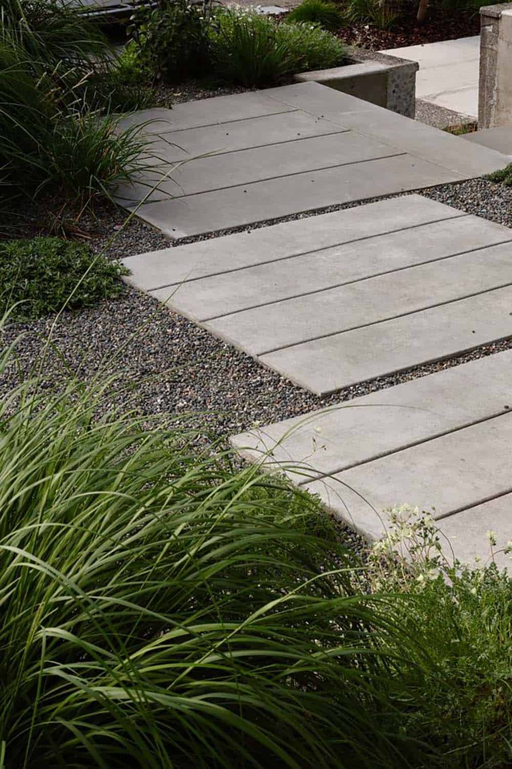 Concrete stepping stone path through gravel and native grasses in the front garden