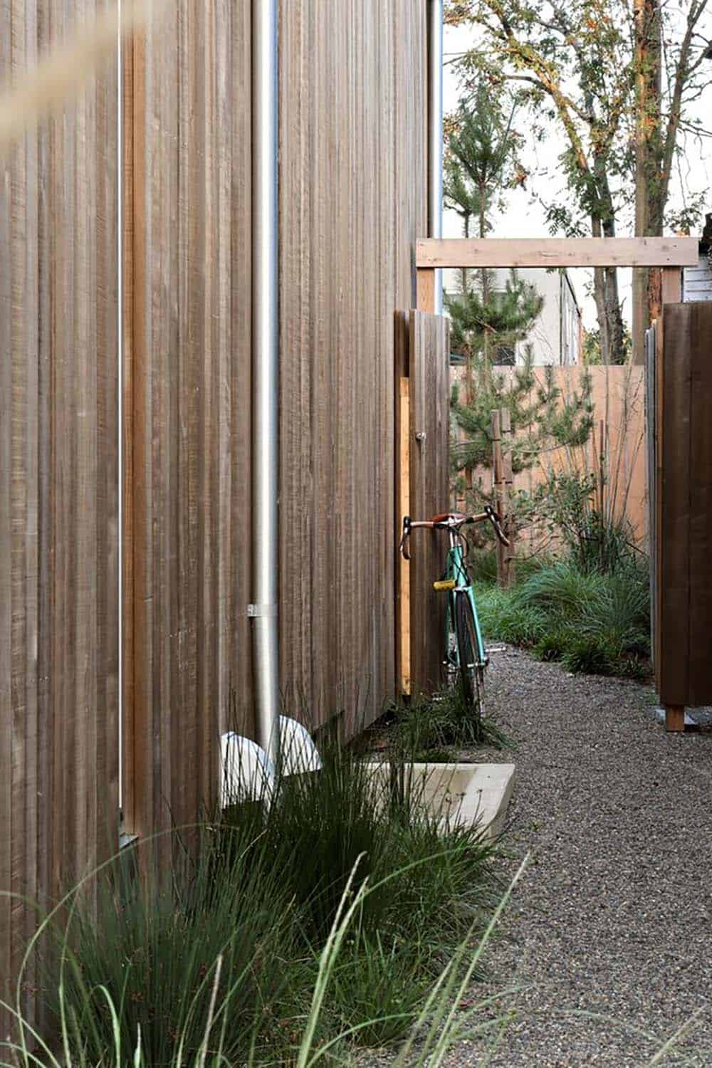 Side passage along the cedar-clad exterior with bicycle and gravel path to the backyard