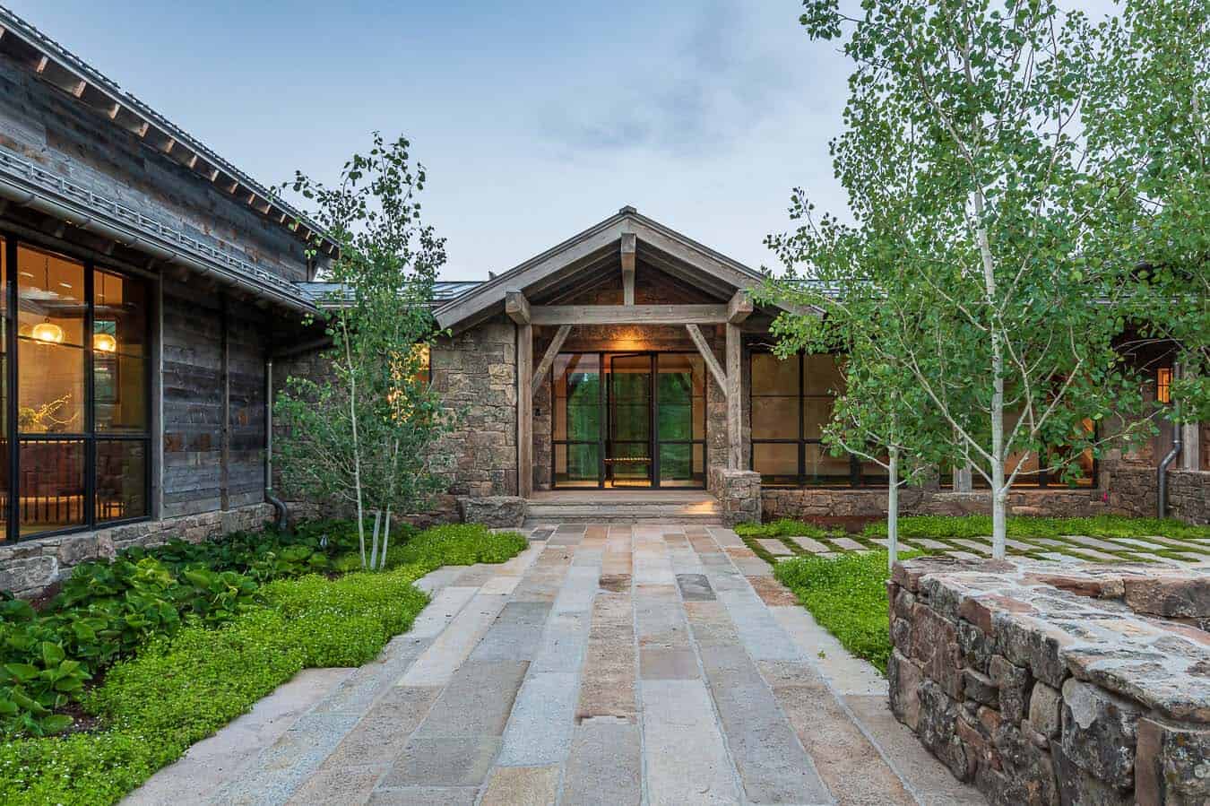 Stone and timber entry with flagstone walkway and aspen trees at dusk