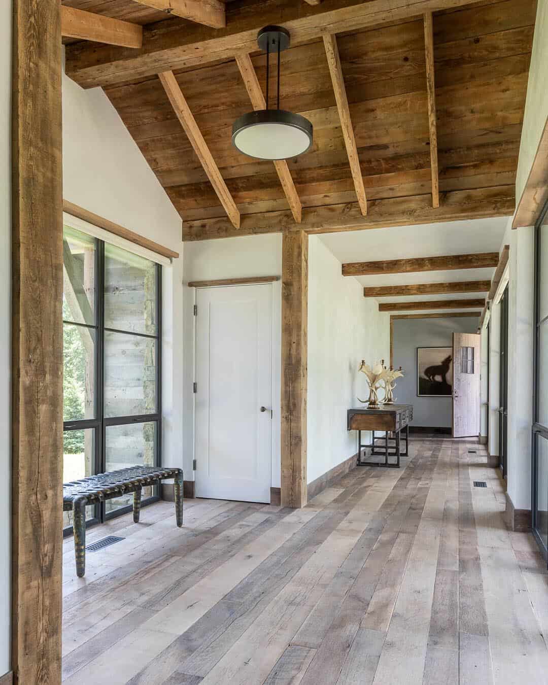Foyer with reclaimed wood beam ceiling, wide-plank floors, and hallway