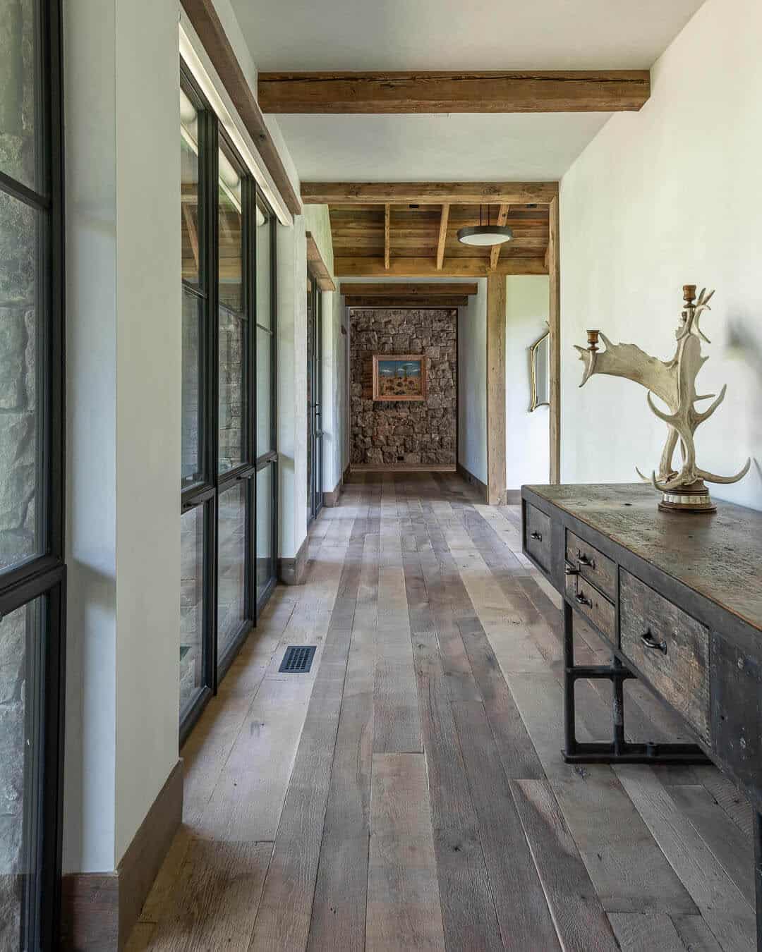 Hallway with exposed timber beams, steel windows, and antler decor on console table