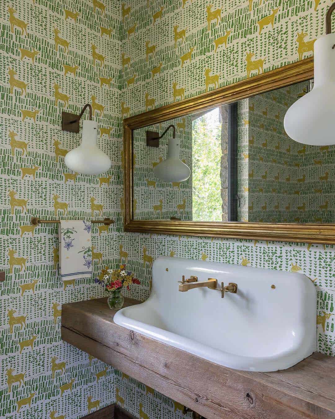 Powder room with deer-print wallpaper, farmhouse sink on wood shelf, and brass fixtures