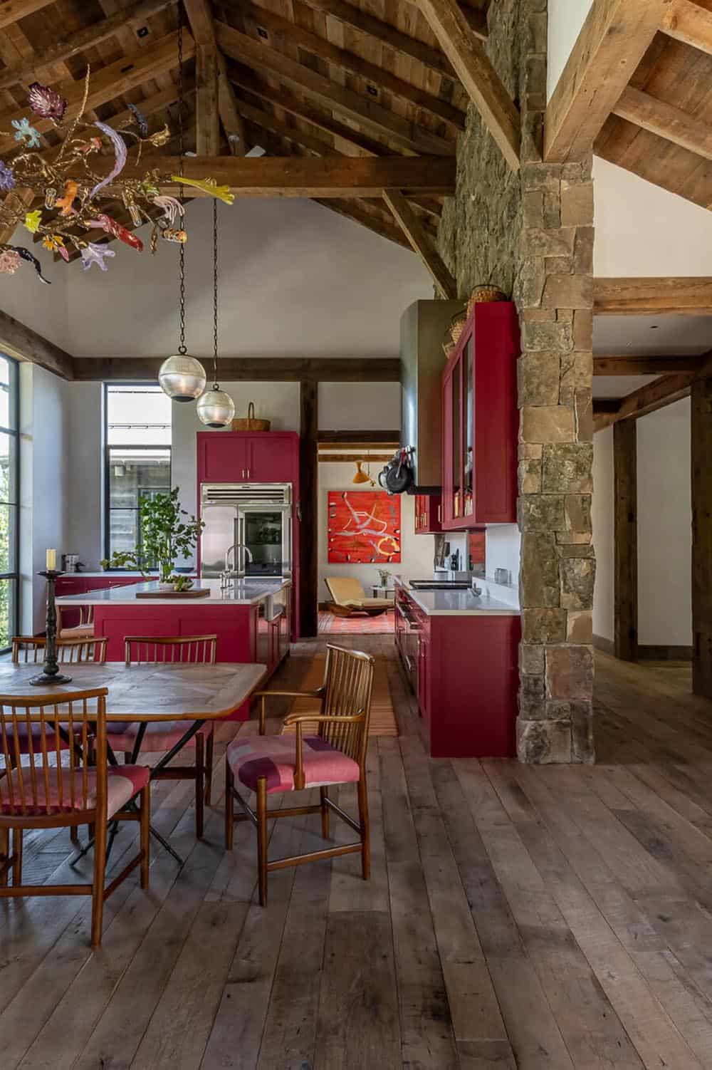 Open kitchen and dining with red cabinets, stone pillar, and timber beam ceiling