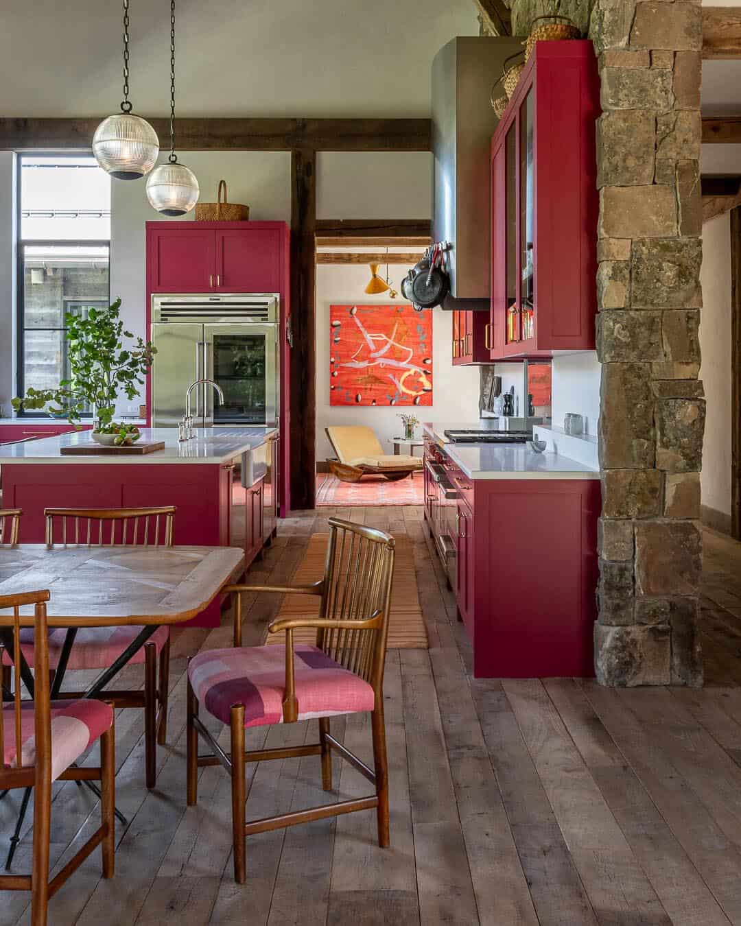 Kitchen with bold red cabinets, stone island pillar, and globe pendant lights