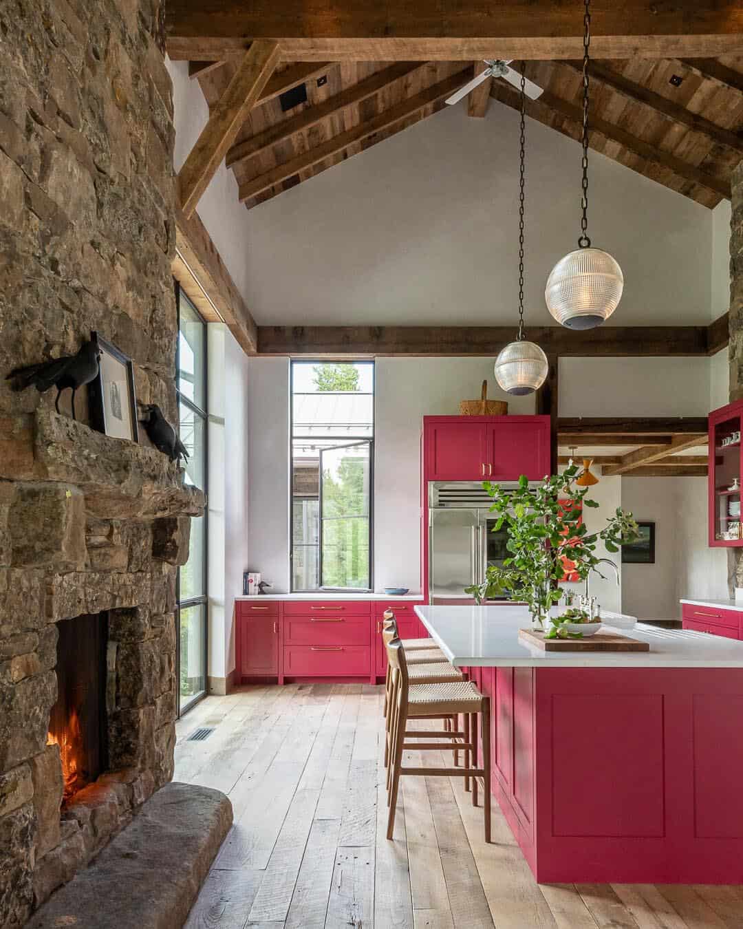 Kitchen with raspberry cabinets, stone fireplace, vaulted ceiling, and globe pendants