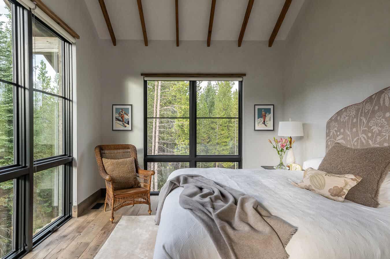 Guest bedroom with forest views, wicker chair, upholstered headboard, and ski art