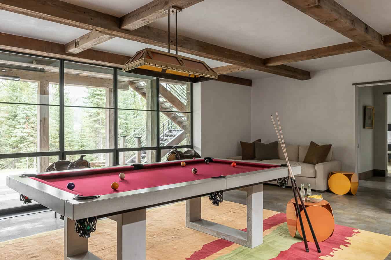 Game room with pool table, timber beams, and floor-to-ceiling forest views