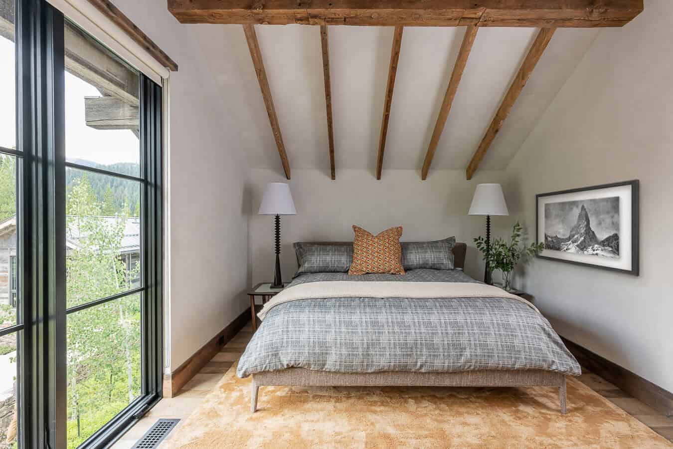 Guest bedroom with vaulted timber ceiling, mountain views, and black-and-white peak art