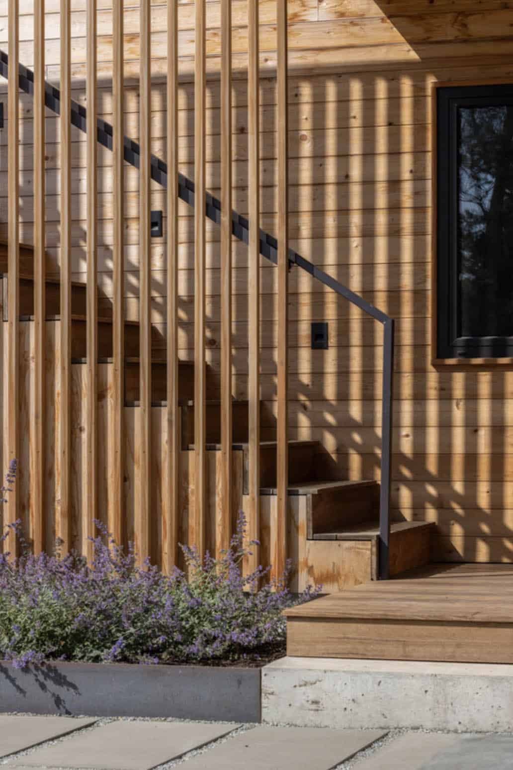 Detail of the cedar slat railing, exterior stairs, and a window, with lavender planted alongside the path