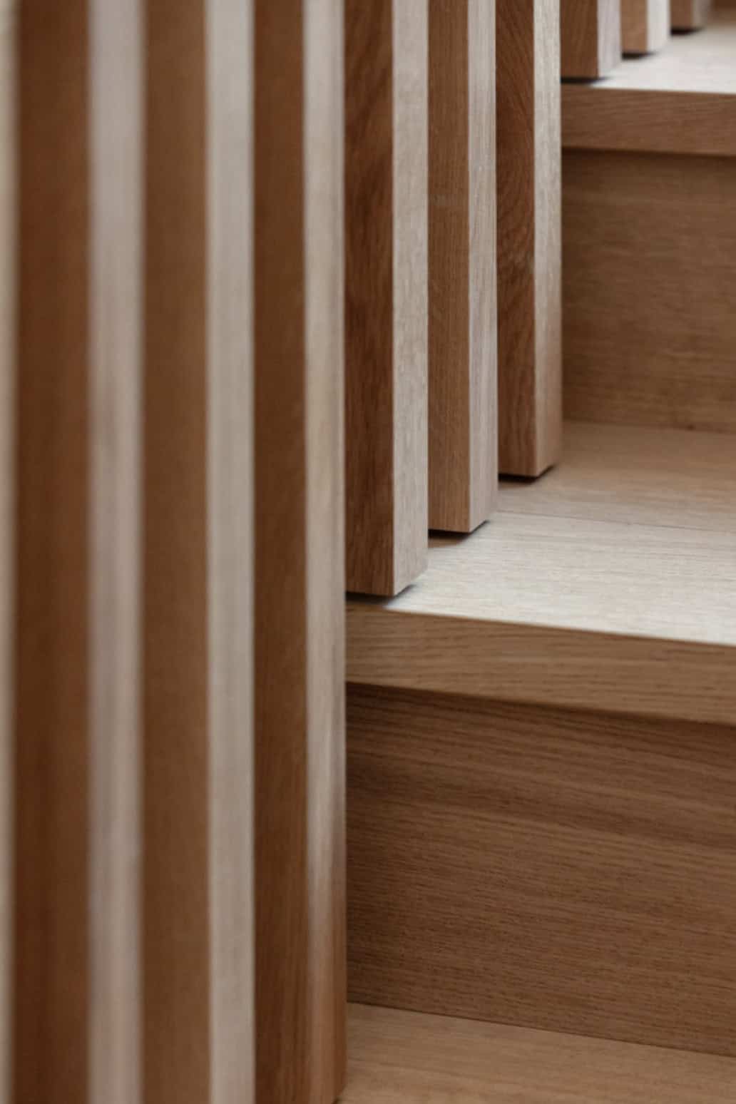 Detail of light oak stair treads and slatted balustrade with soft natural light