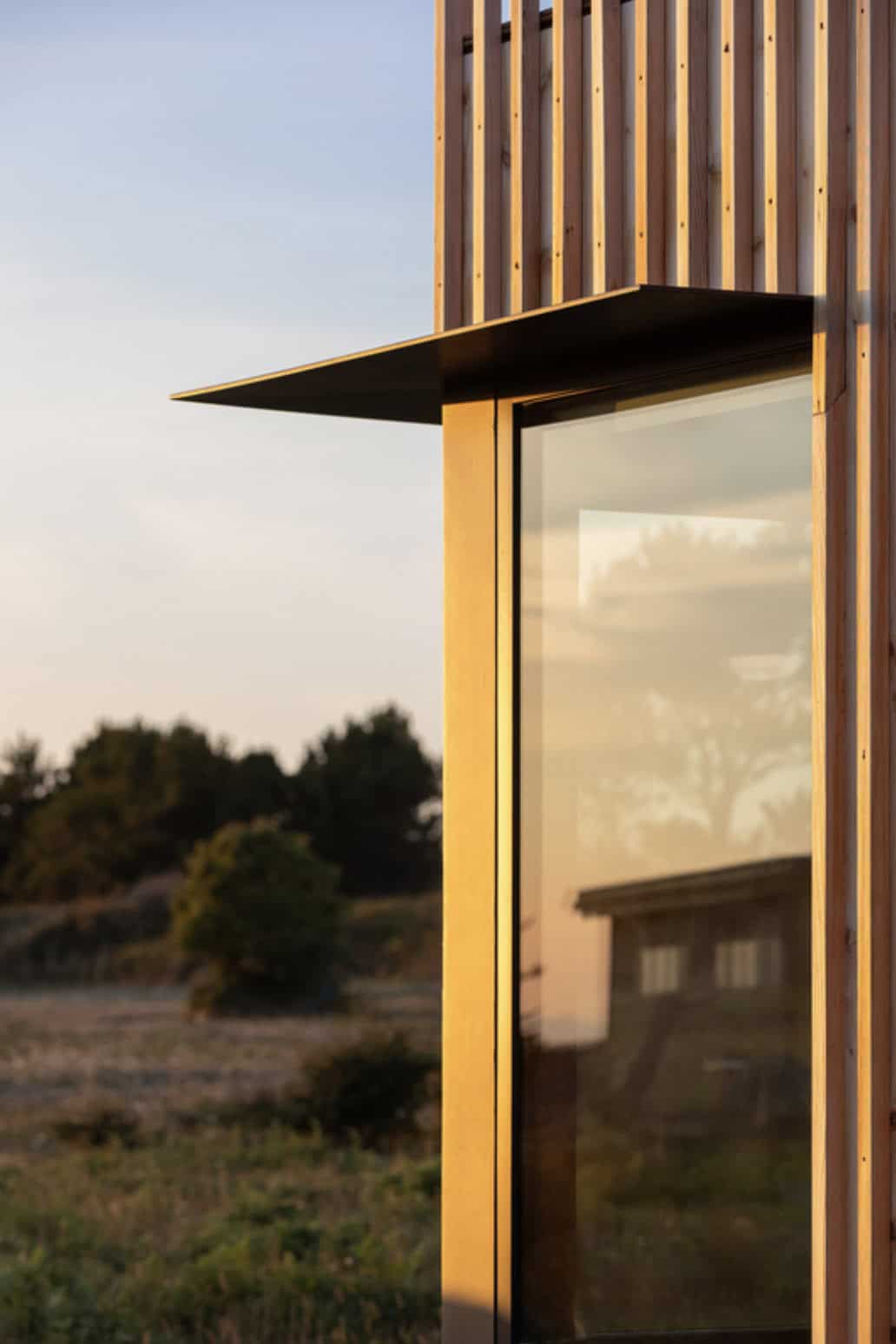 Close-up of a cantilevered metal roof detail atop the cedar-clad tower at golden hour