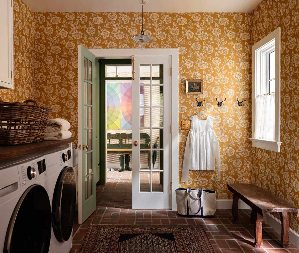 Laundry room with mustard yellow floral wallpaper, front-load washer and dryer, brick floor, and French doors