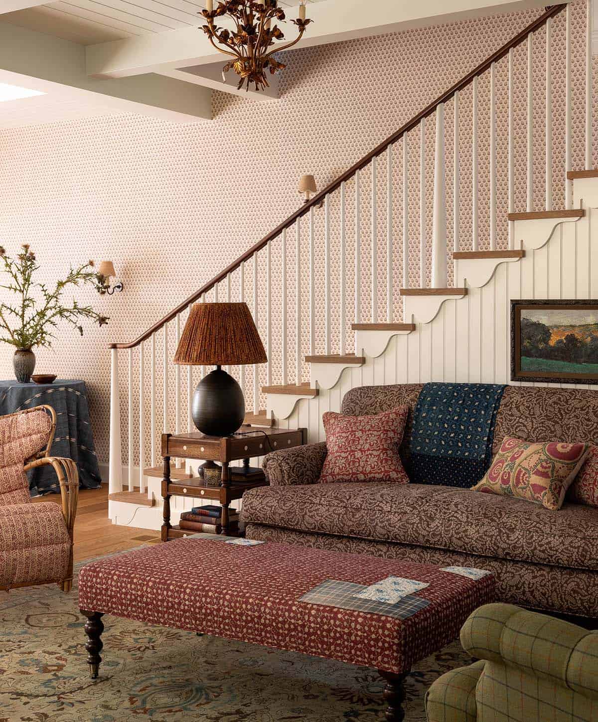 Living room staircase with delicate printed wallpaper, scalloped stair skirt, and layered patterned upholstery