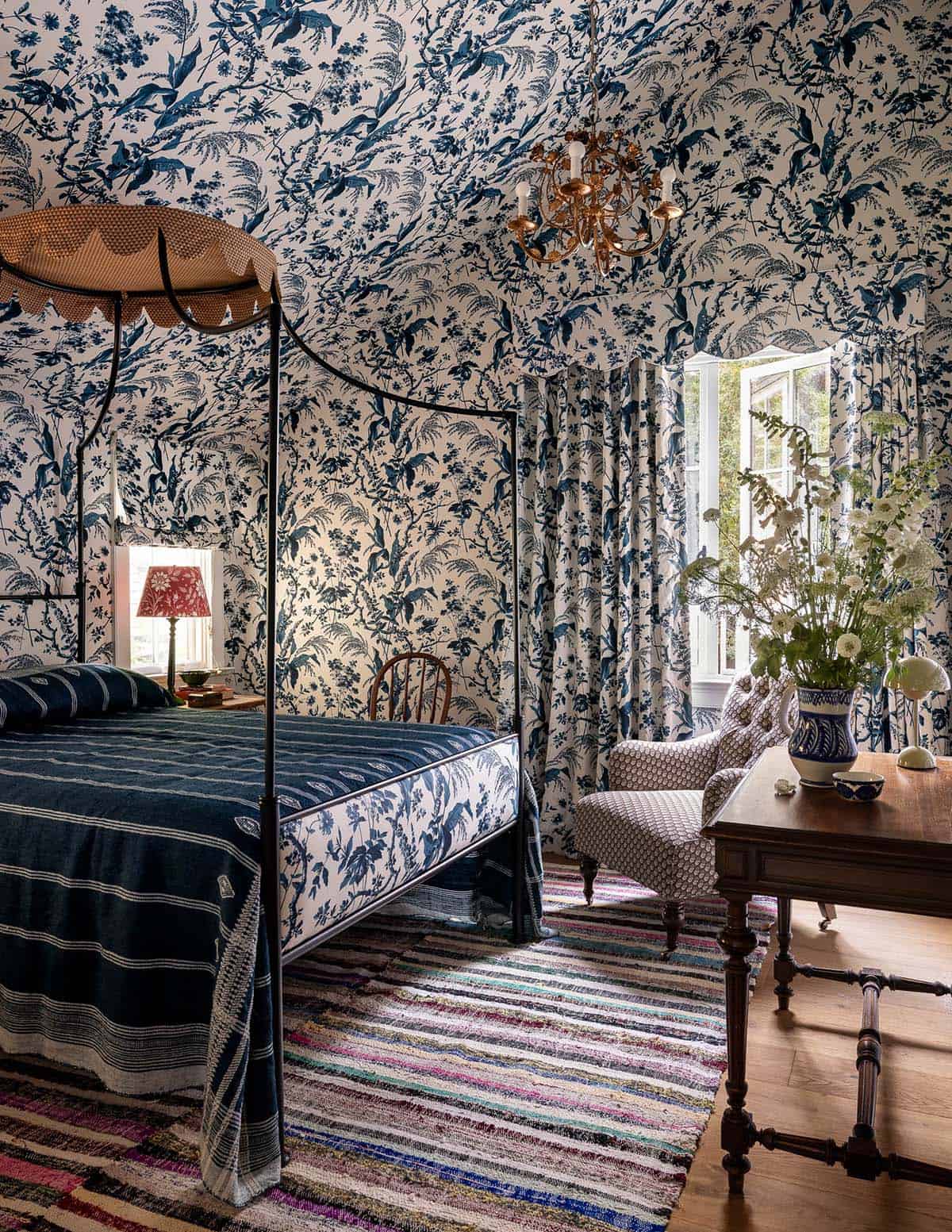 Guest bedroom with bold blue-and-white toile wallpaper floor-to-ceiling, four-poster bed, and matching curtains