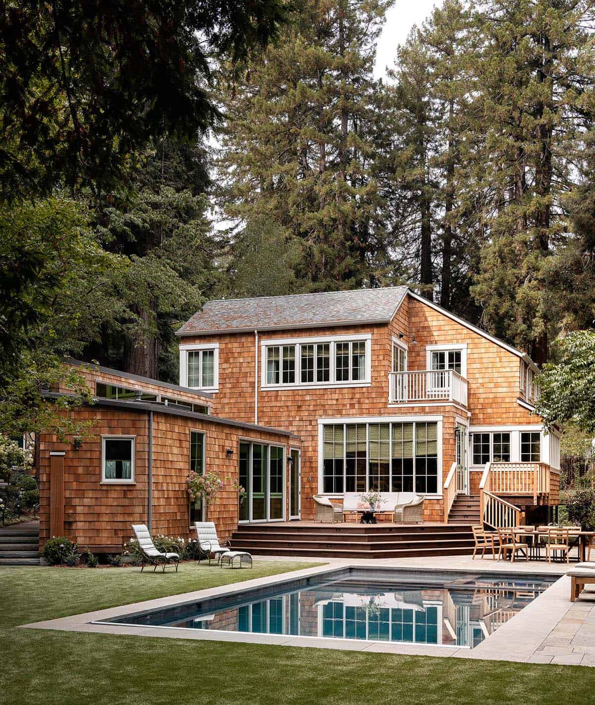 Cedar shingle home rear exterior with lap pool, raised wood deck, and redwood forest backdrop