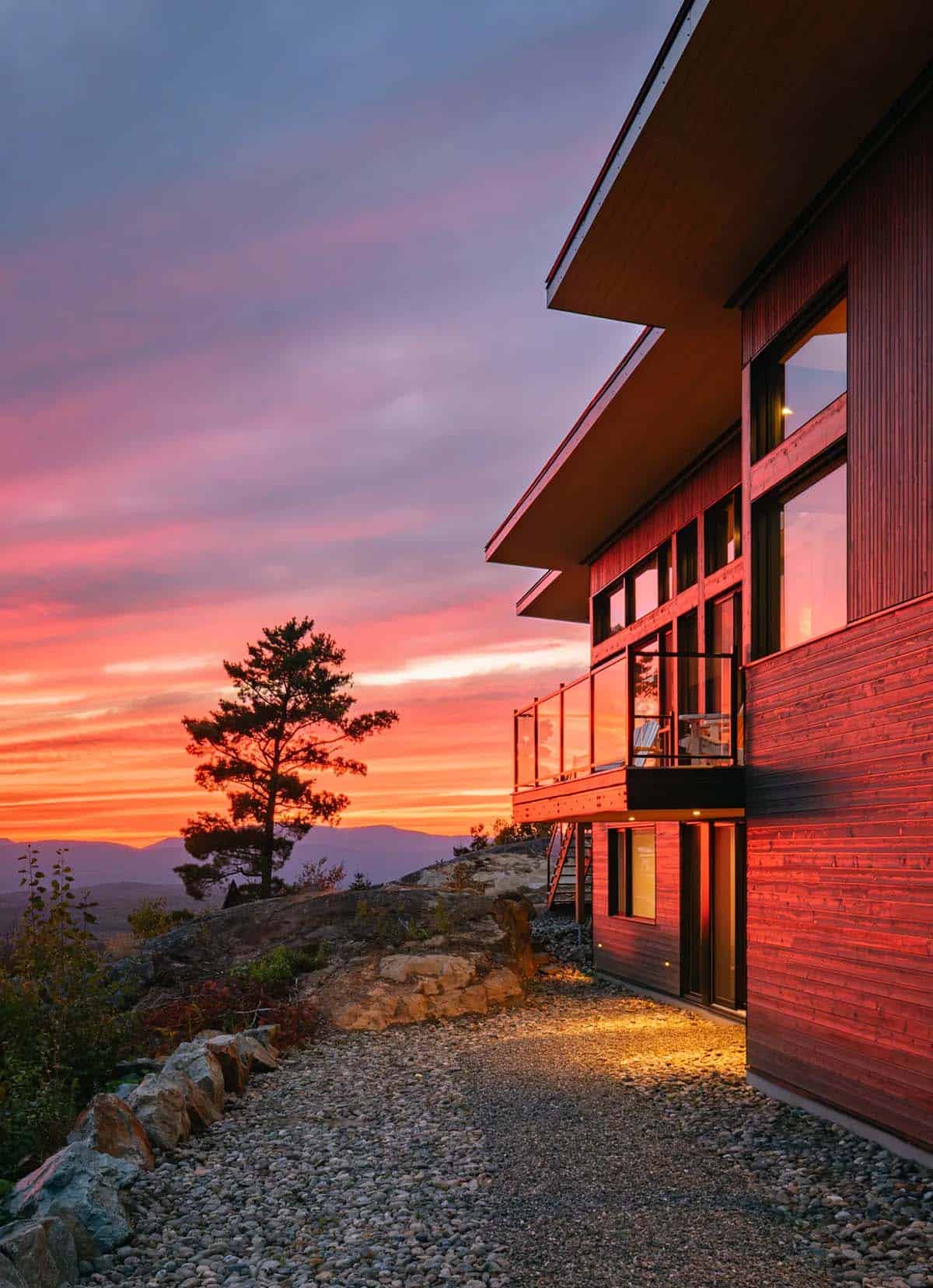 Side view of house exterior bathed in dramatic red and orange sunset light 