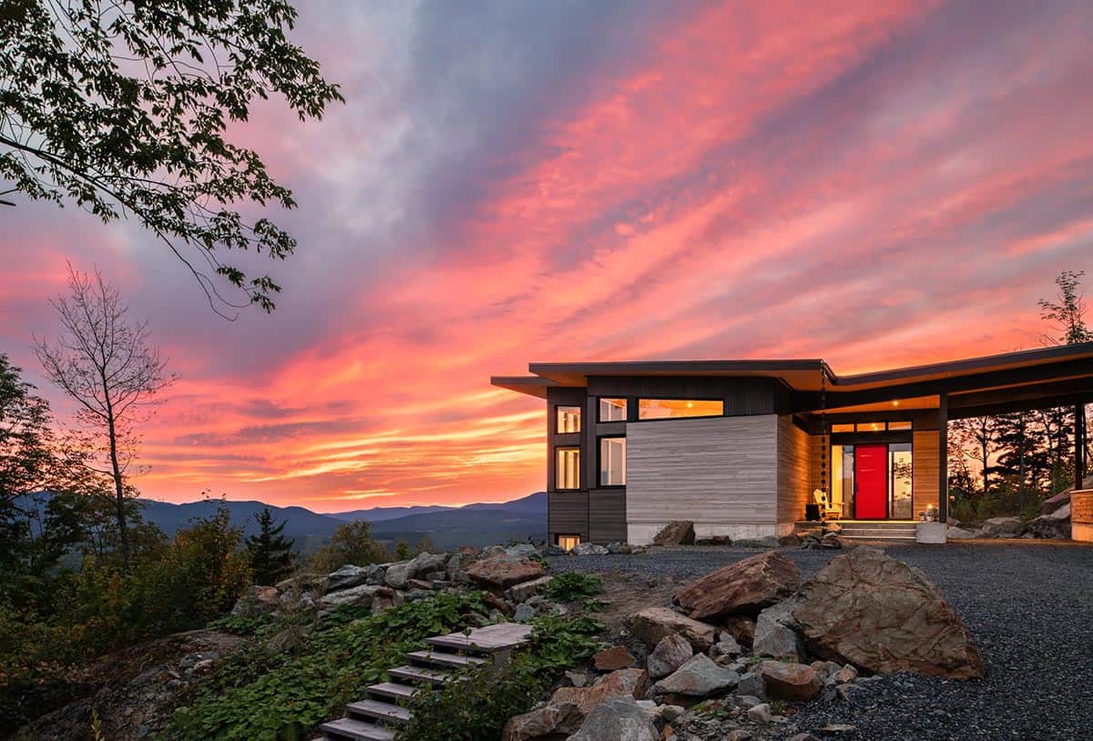 Front entry with red door glowing against vivid pink and orange sunset sky 