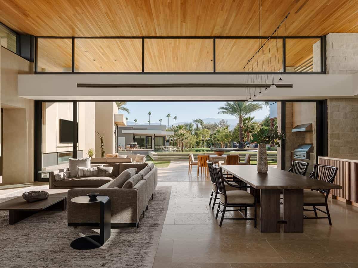 Open-plan living and dining room with wood-plank ceiling, large sliding glass doors opening to a pool and mountain view