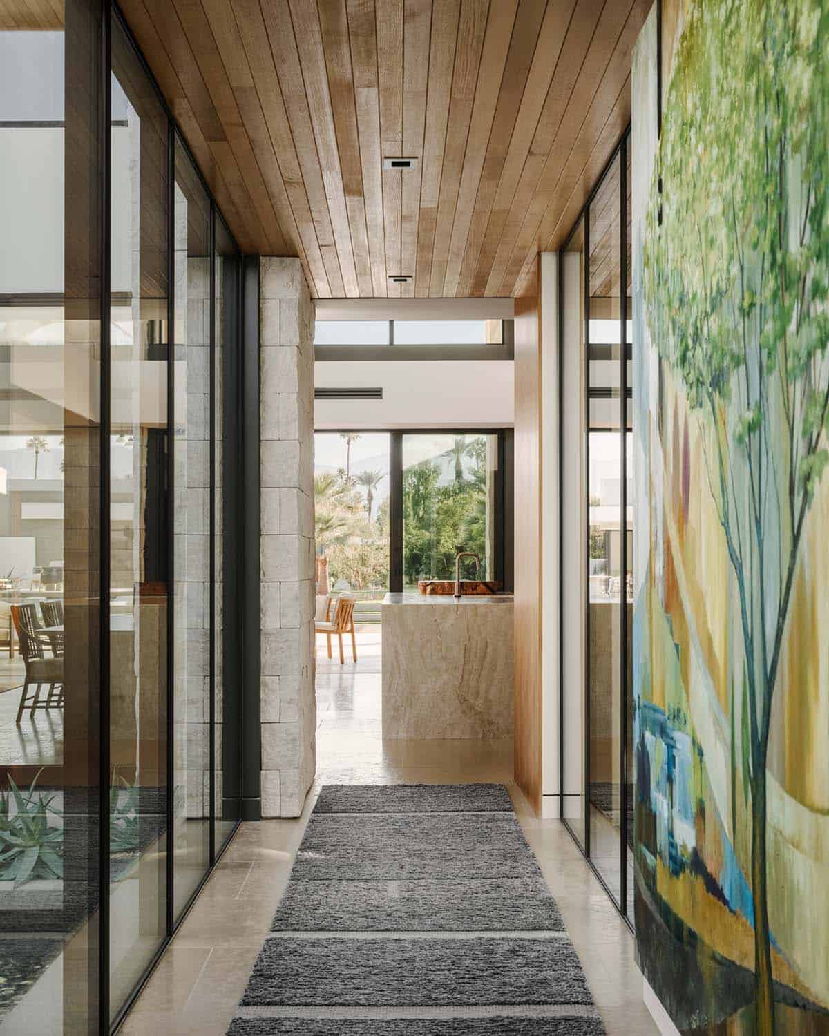 Entry hallway with wood-plank ceiling, limestone block columns, stone tile floor, and large landscape painting on the wall