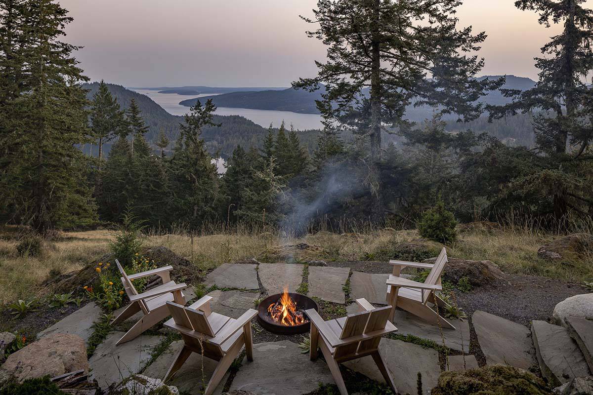Fire pit seating area with Adirondack chairs overlooking island and water views at sunset, Orcas Island