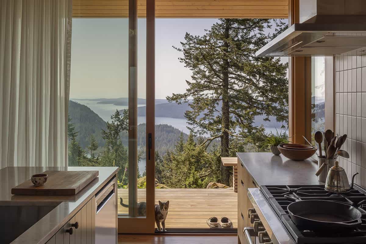 Kitchen with white cabinetry and gas range with sliding glass door open to deck and sweeping water views