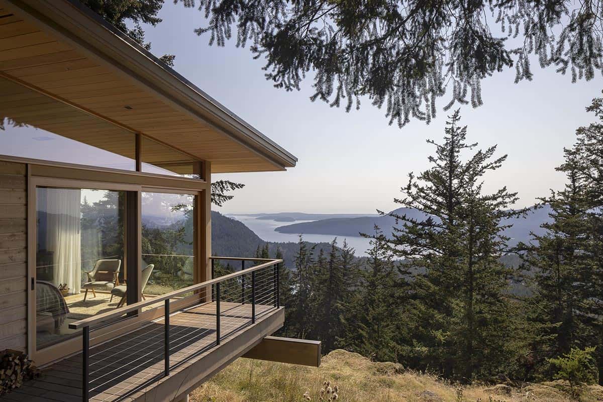 Elevated wood deck with cable railing and panoramic views over forested hillside and island waterway