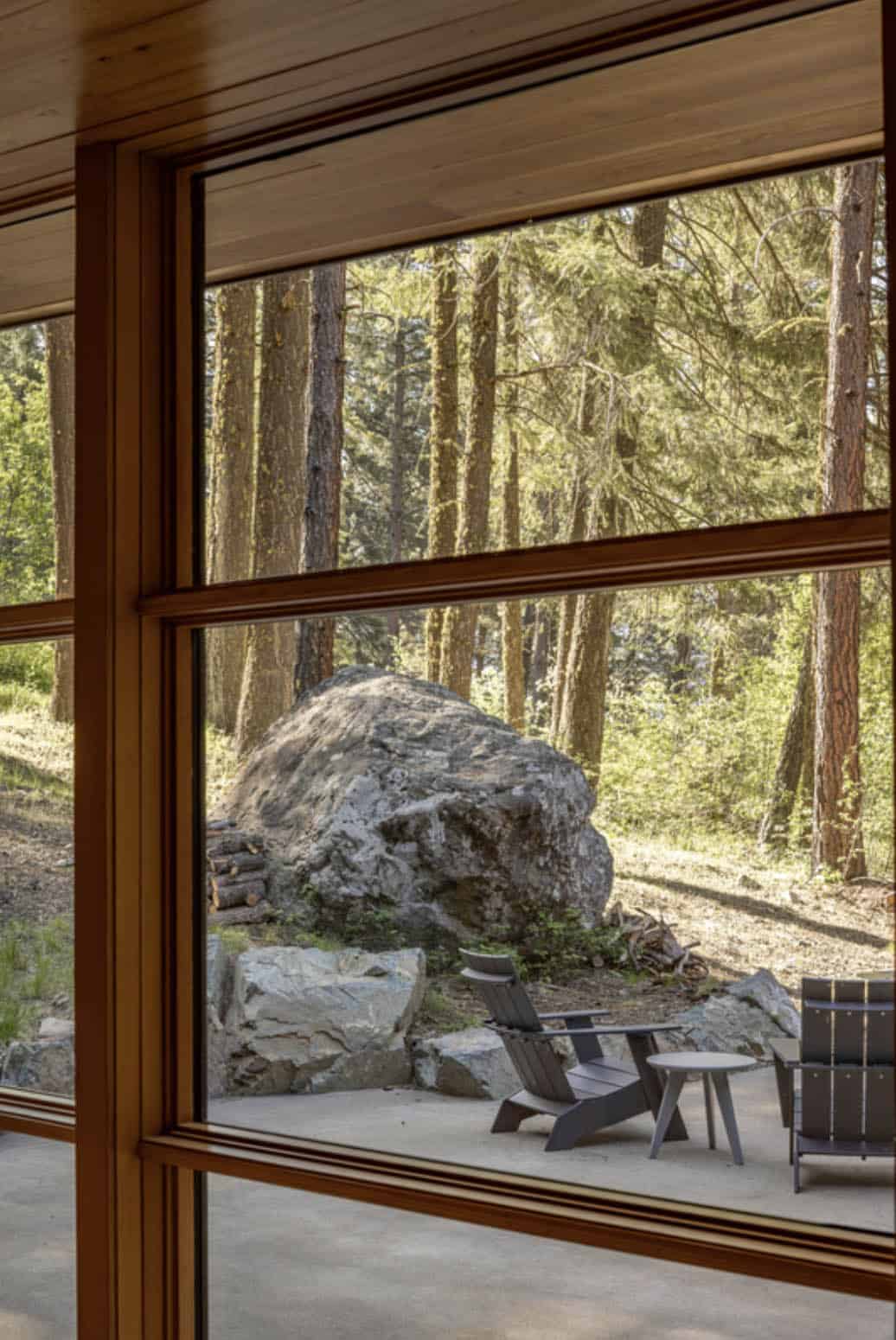 View through wood-framed window to large boulder and patio seating