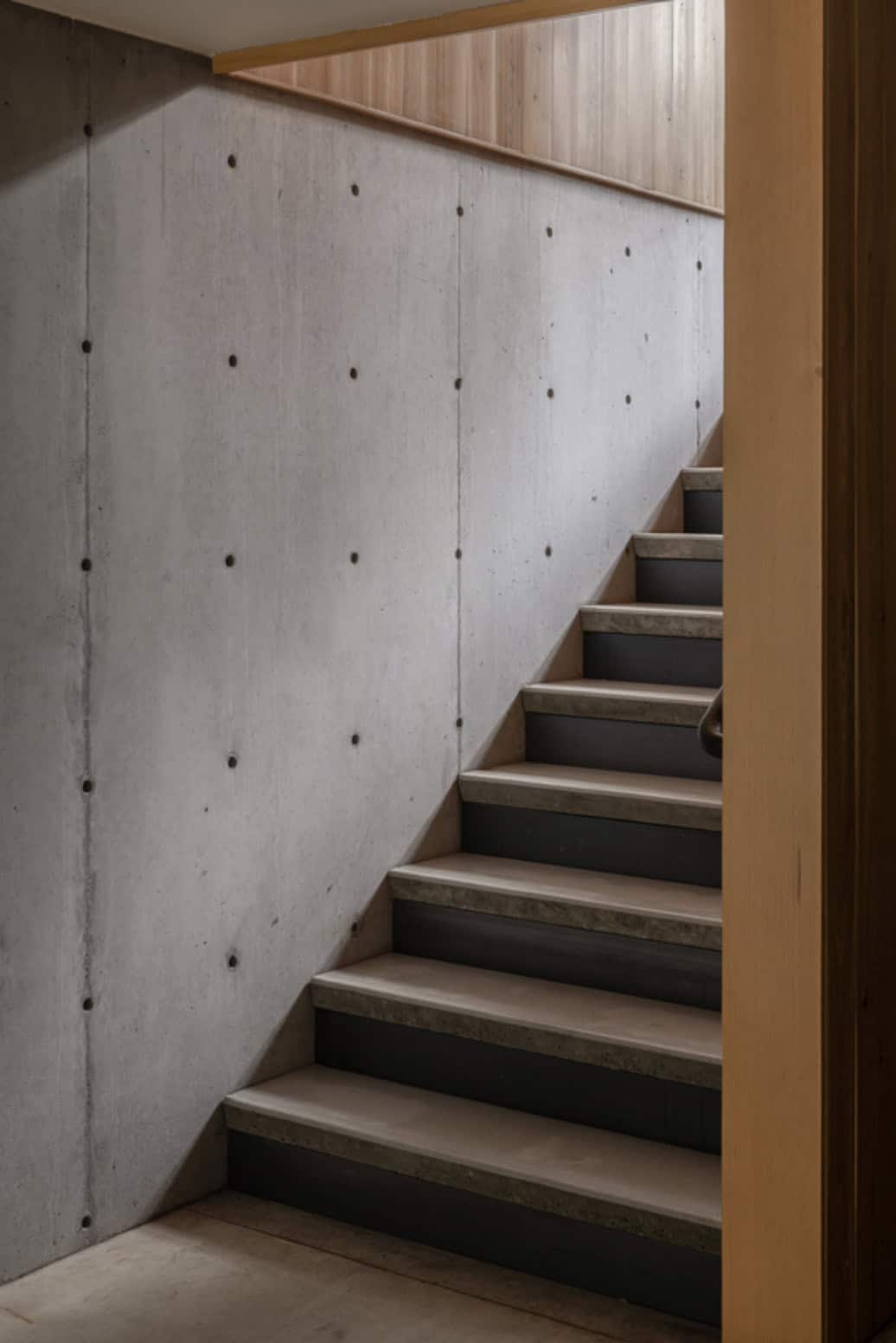 Concrete staircase with board-formed concrete wall and wood trim
