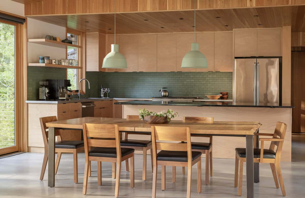 Modern kitchen with green tile backsplash, birch cabinets, and wood dining table
