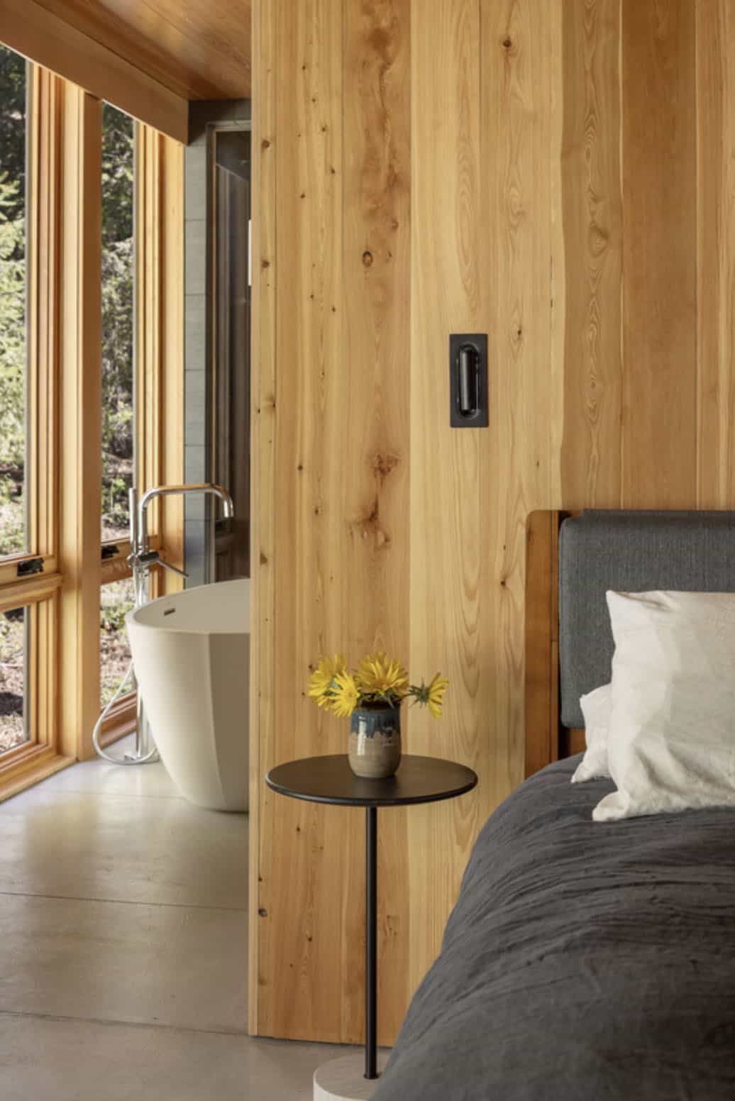 Primary bedroom with Douglas fir wall, freestanding tub, and forest views