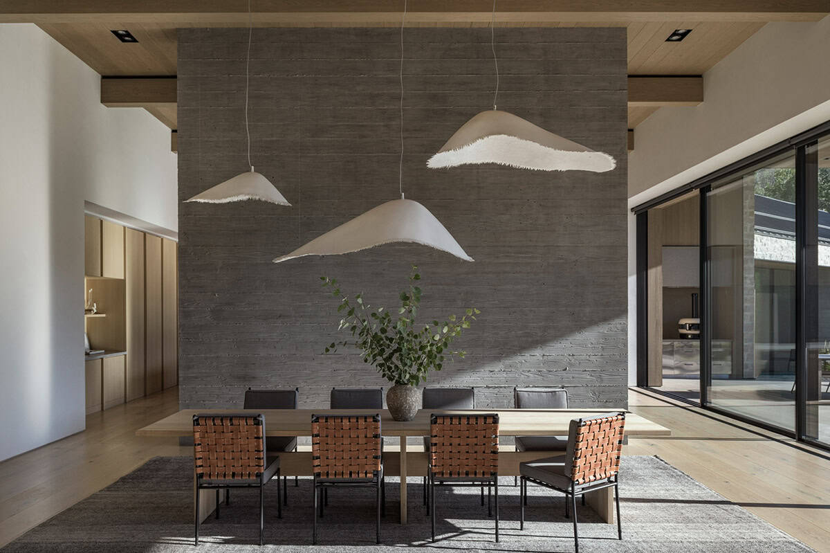 Dining room with cloud-shaped pendant lights hanging before a concrete accent wall