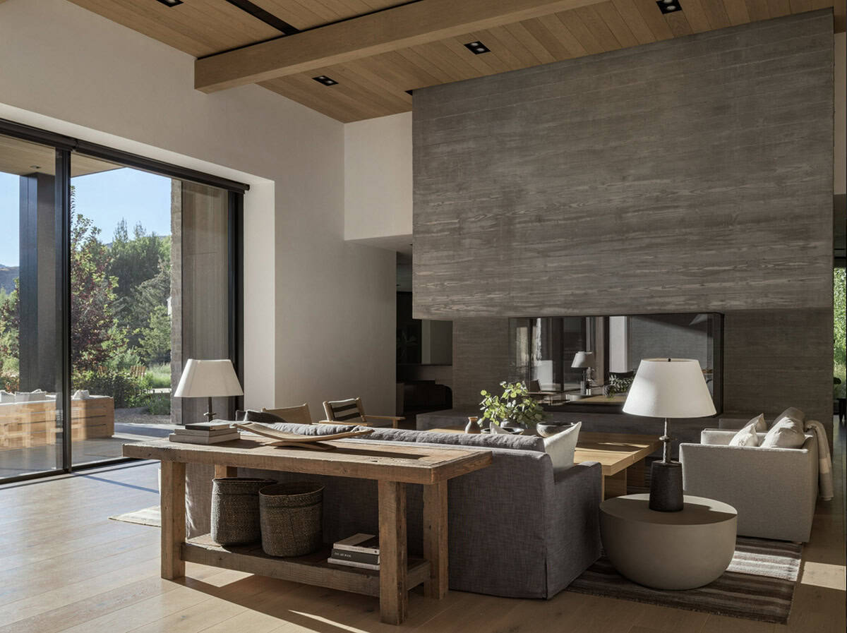 Living room with double-sided concrete fireplace, reclaimed wood console, and upholstered seating